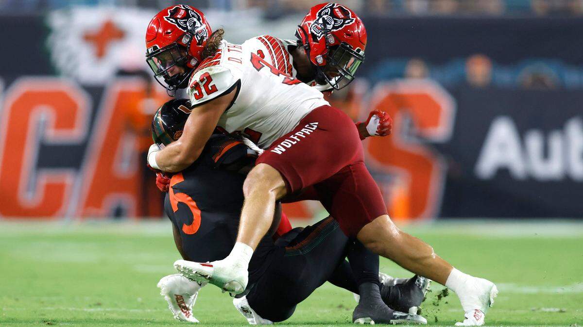 N.C. State linebacker Drake Thomas (32) tackles Miami wide receiver Key’Shawn Smith (5) during the first half of N.C. State’s game against Miami at Hard Rock Stadium in Miami Gardens, Fla. Saturday, Oct. 23, 2021.