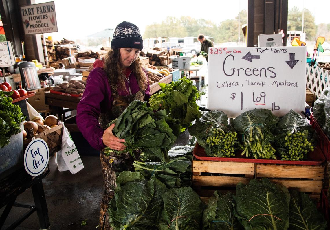 Tammy Woodall of Tart Farms preps collard greens for sale at the State Farmers Market in Raleigh.