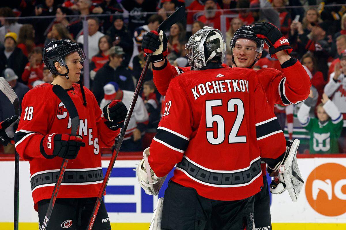 Carolina Hurricanes goaltender Pyotr Kochetkov (52) is congratulated by Andrei Svechnikov, right, and Jack Drury (18) following his win over the Pittsburgh Penguins in an NHL hockey game in Raleigh, N.C., Sunday, Dec. 18, 2022. (AP Photo/Karl B DeBlaker)