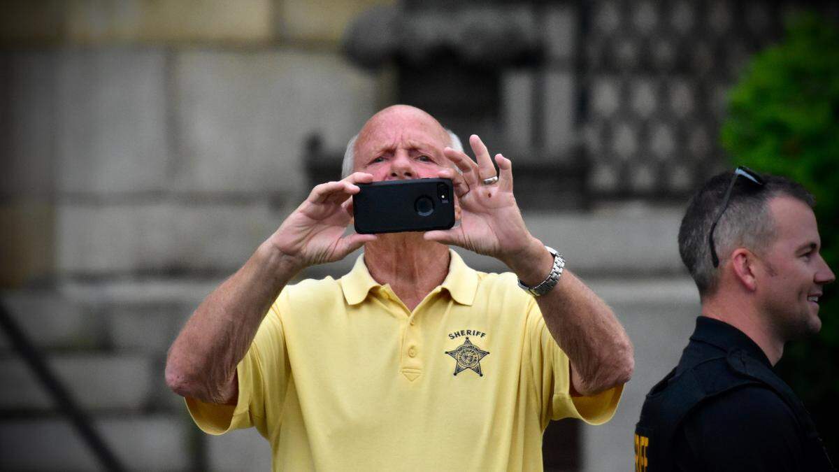Just before the start of an 8 p.m. curfew in Graham, Sheriff Terry Johnson points his phone toward an almost empty street corner in Court Square where protesters had attempted to demonstrate earlier in the day on June 28, 2020.