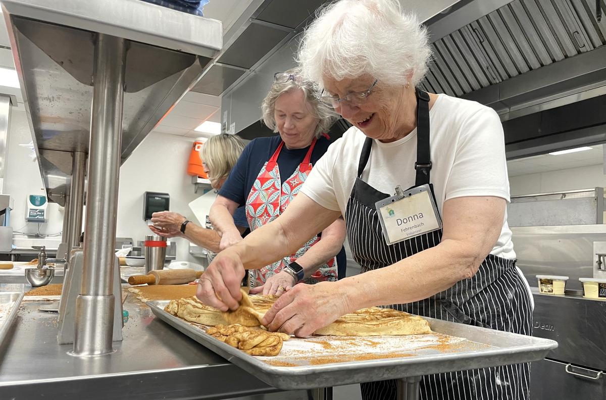 Volunteers Cheryl Carnahan, at left, and Donna Fehrenbach make quick work of the dough Friday, Oct. 4, 2024, at St. Thomas More Catholic Church in Chapel Hill. Fehrenbach said the cinnamon roll was to bring some fun and laughter to SECU Family House guests.