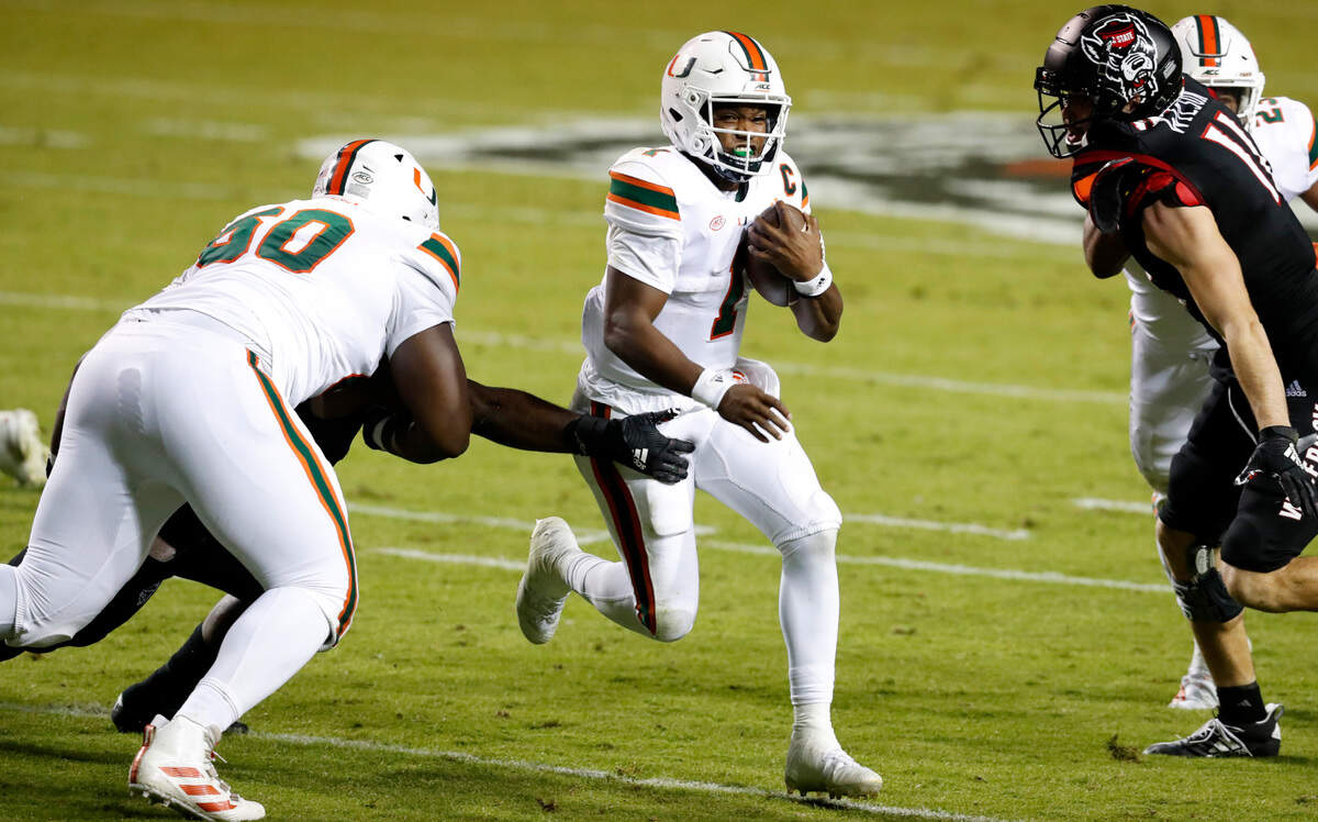 Miami quarterback D’Eriq King (1) runs past N.C. State linebacker Isaiah Moore (1), left during the first half of N.C. State’s game against Miami at Carter-Finley Stadium in Raleigh, N.C., Friday, Nov. 6, 2020.