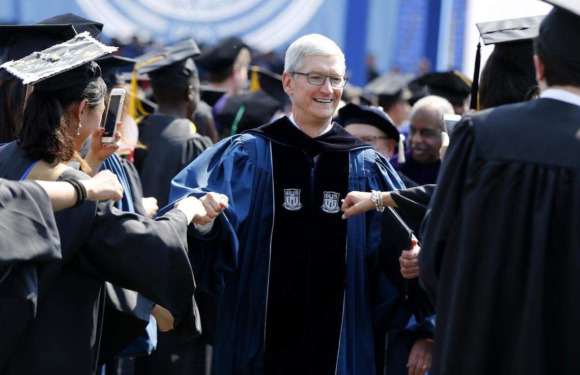 Apple CEO Tim Cook fist bumps graduates while leaving Duke University’s commencement on Monday. His company is considering locating some of its operations in the Triangle.