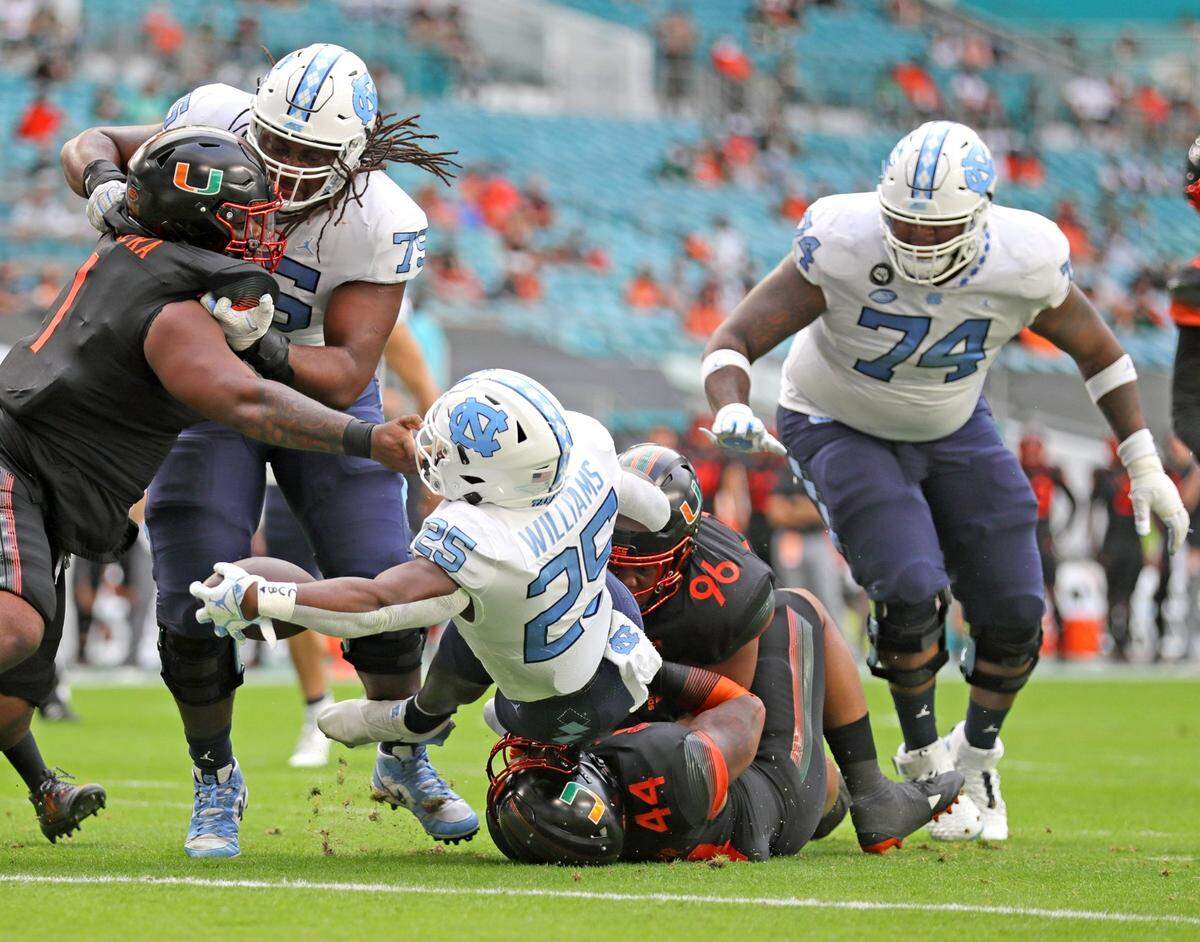 Miami Hurricanes defensive lineman Jonathan Ford (96) fails to stop North Carolina Tar Heels running back Javonte Williams (25) as he scores a first quarter touchdown at Hard Rock Stadium In Miami Gardens, Florida, Saturday, December 12, 2020.