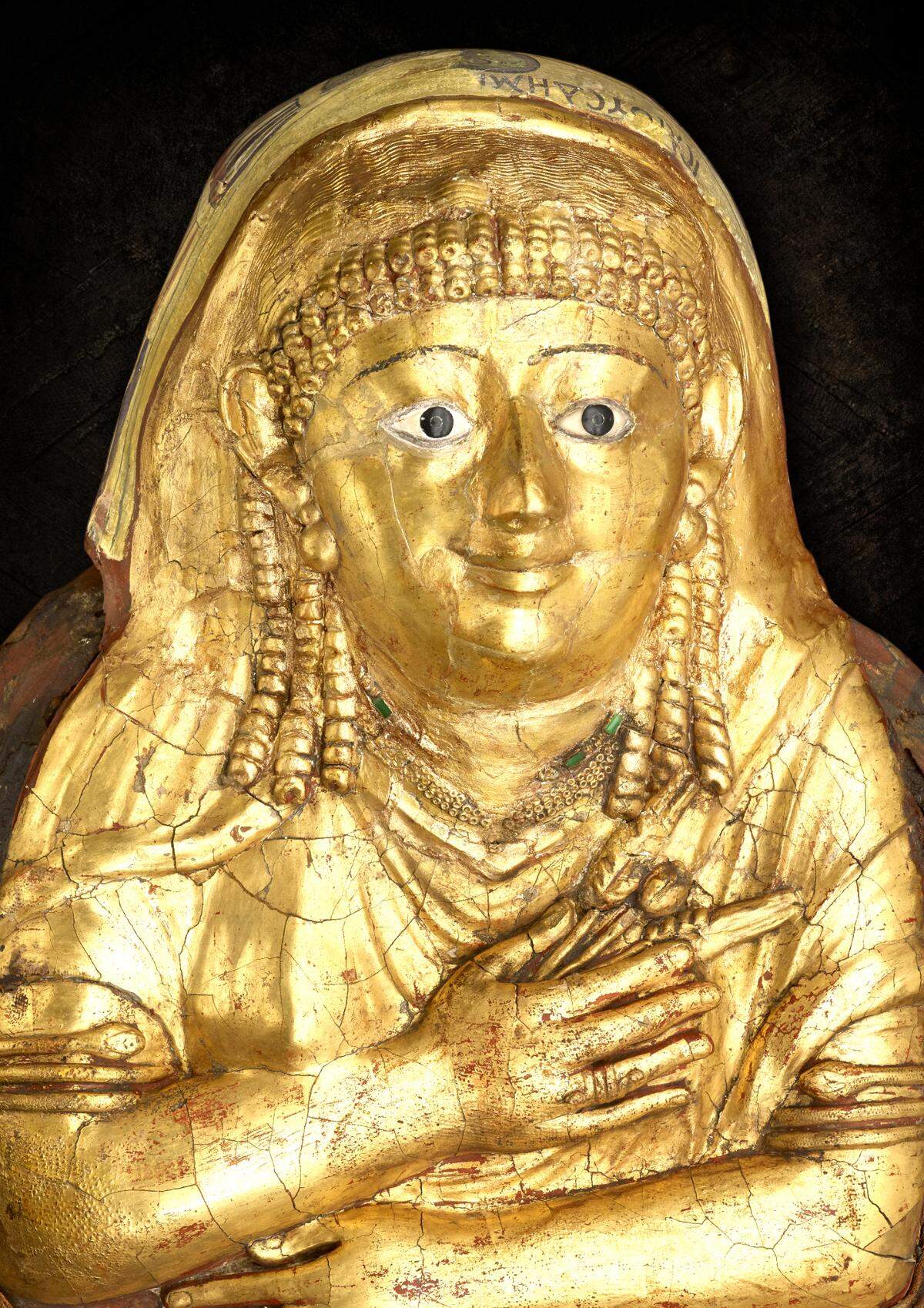 Egyptian, from Hawara, Mummy of a woman called Isaious (detail), 1st century C.E., human remains, linen, plaster, and gold leaf, Manchester Museum. The gilded mask of this mummy shows the deceased with a Roman hairstyle and jewelry.