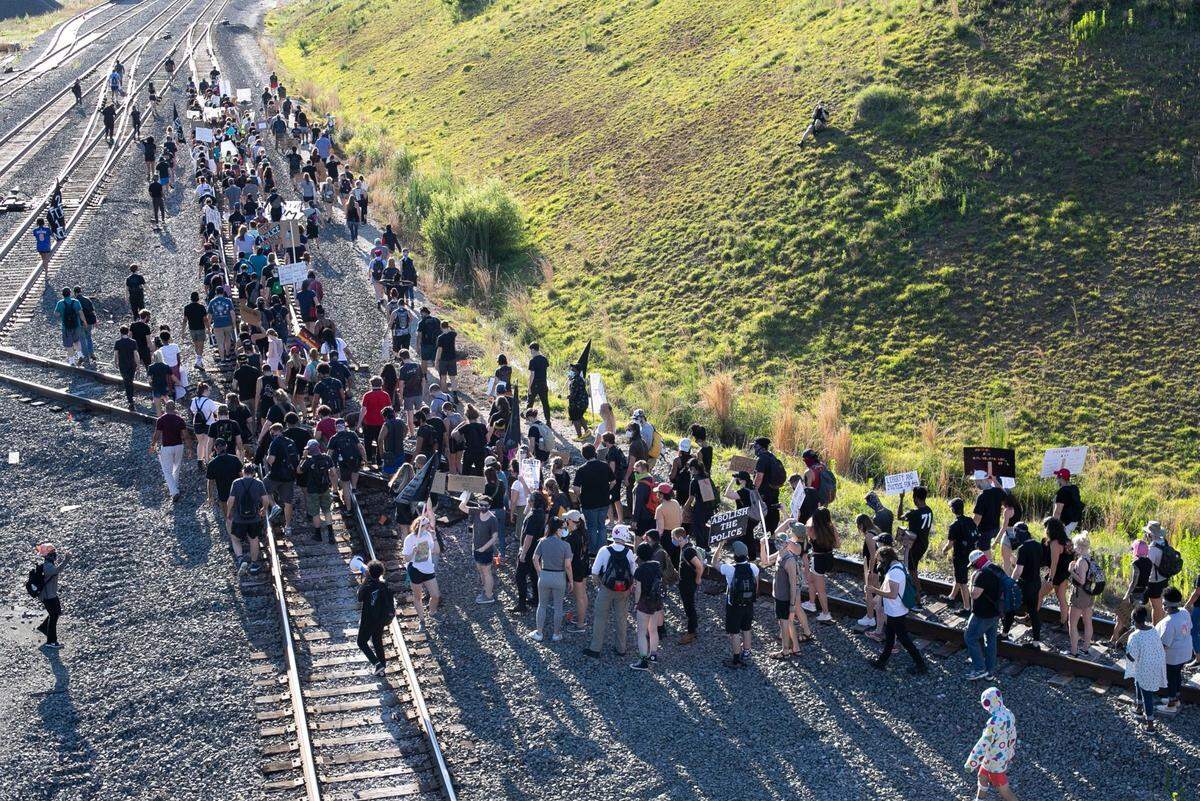 Protesters march along the railroad tracks beneath the Boylan Avenue Bridge to Central Prison for a rally on police and orison reform on Saturday, June 13, 2020 in Raleigh, N.C.