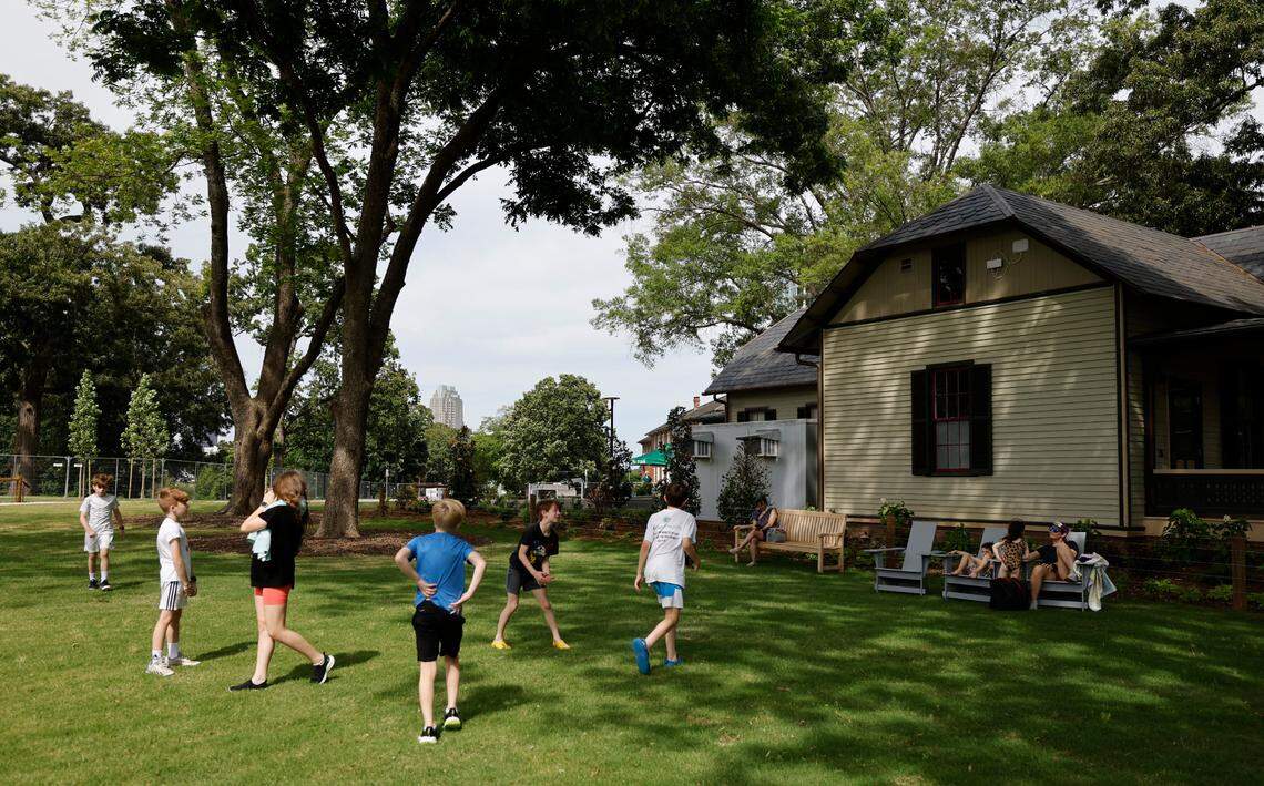 Children play outside the House of Many Porches Market at Gipson Play Plaza at Dix Park.