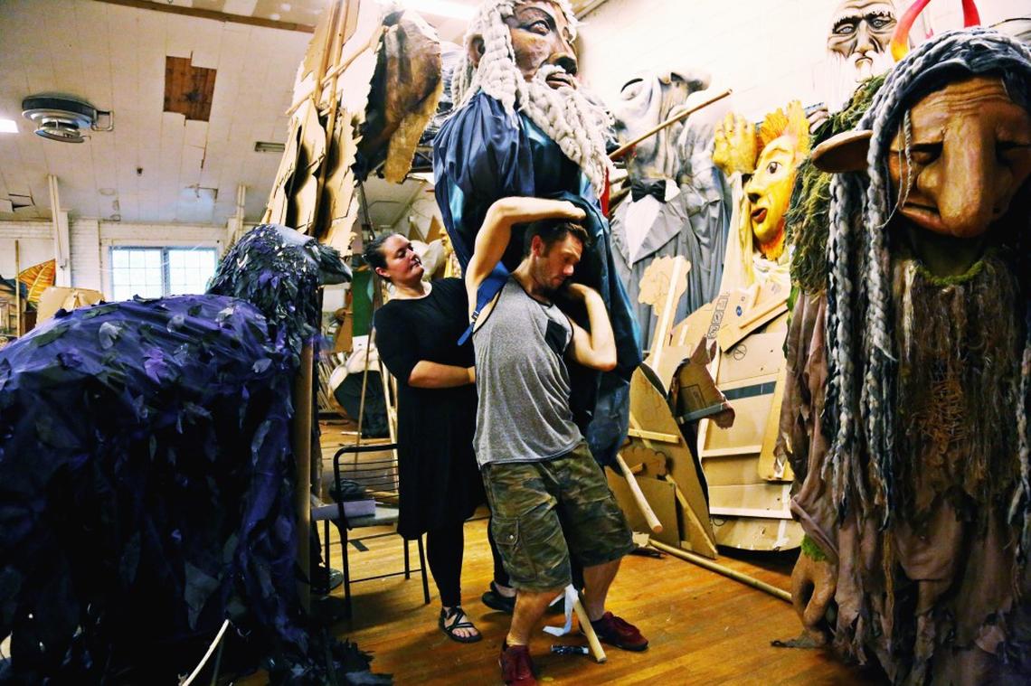 From left, Lawruh Lindsey helps Tommy Noonan into a large puppet during rehearsal in Saxapahaw July 26, 2018, for Paperhand Puppet Intervention’s “In the Heart of the Fire.”