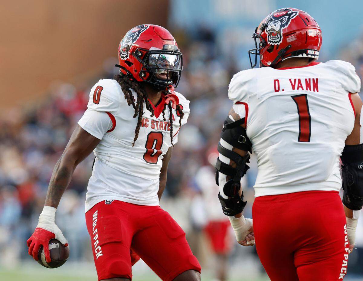 N.C. State linebacker Sean Brown (0) celebrates with Davin Vann (1) after Brown recovered a fumble forced by Vann during the first half of N.C. State’s game against UNC at Kenan Stadium in Chapel Hill, N.C., Saturday, Nov. 30, 2024.