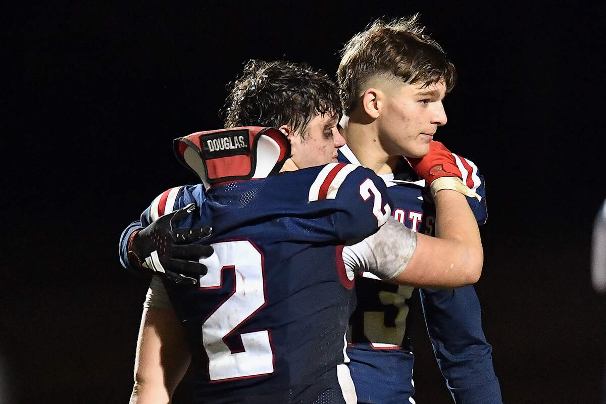 Apex Friendship running back Sam Clodfelter (2) embraces quarterback Tyler Goebbel (13) after their second round overtime loss to Rolesville. The Apex Friendship Patriots and the Rolesville Rams met in  the second round of the  NCHSAA 8A Playoff game in Apex, N.C. on November 14, 2025. Rolesville wins 14-7 in overtime.