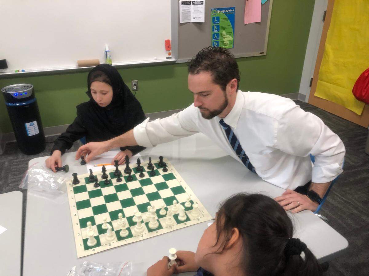 Afghan refugee students at Stough Elementary School learn how to play chess on April 1, 2022 in Raleigh, N.C. Pictured clockwise are third-grade student Anita, principal Chris Cox and third-grade student Nazaneen.