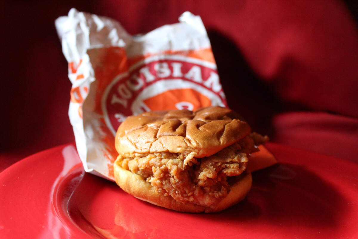Popeyes’ crispy chicken sandwich is topped with pickle slices and classic mayo between two toasted brioche buns.