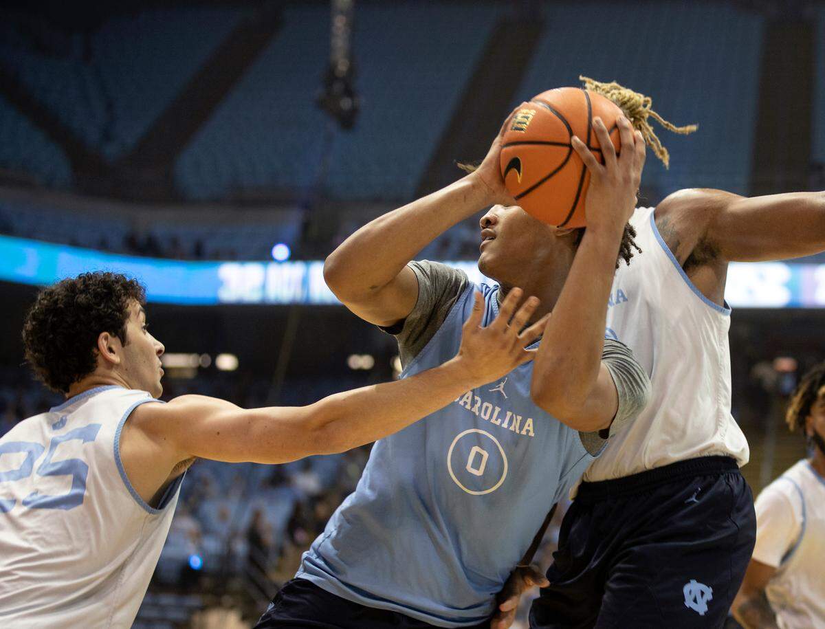 Seth Trimble looks to pass while driving between Creighton Lebo and Armando Bacot during a scrimmage at “Live Action with Carolina Basketball” at the Dean E. Smith Center on Friday, Oct. 7, 2022, in Chapel Hill, N.C.