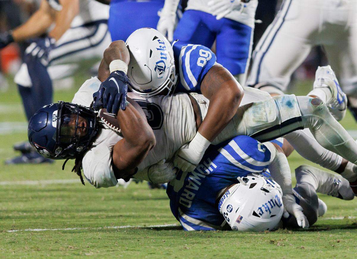 Connecticut’s Cam Edwards is brought down by Duke’s Alex Howard and Aaron Hall during the second half of the Blue Devils’ 26-21 win on Saturday, Sept. 14, 2024, at Wallace Wade Stadium in Durham, N.C.