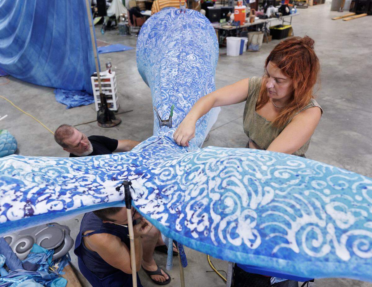 Ginger Lipscomb, Donovan Zimmerman and Hunni Palmer work on a whale puppet at Paperhand Puppet Intervention’s new studio on Saturday, July 26, 2025, in Graham, N.C. When remnants of Tropical Storm Chantal brought floodwaters from the Haw River into the company’s studio, the organization was forced to expedite its scheduled move date to a new space.