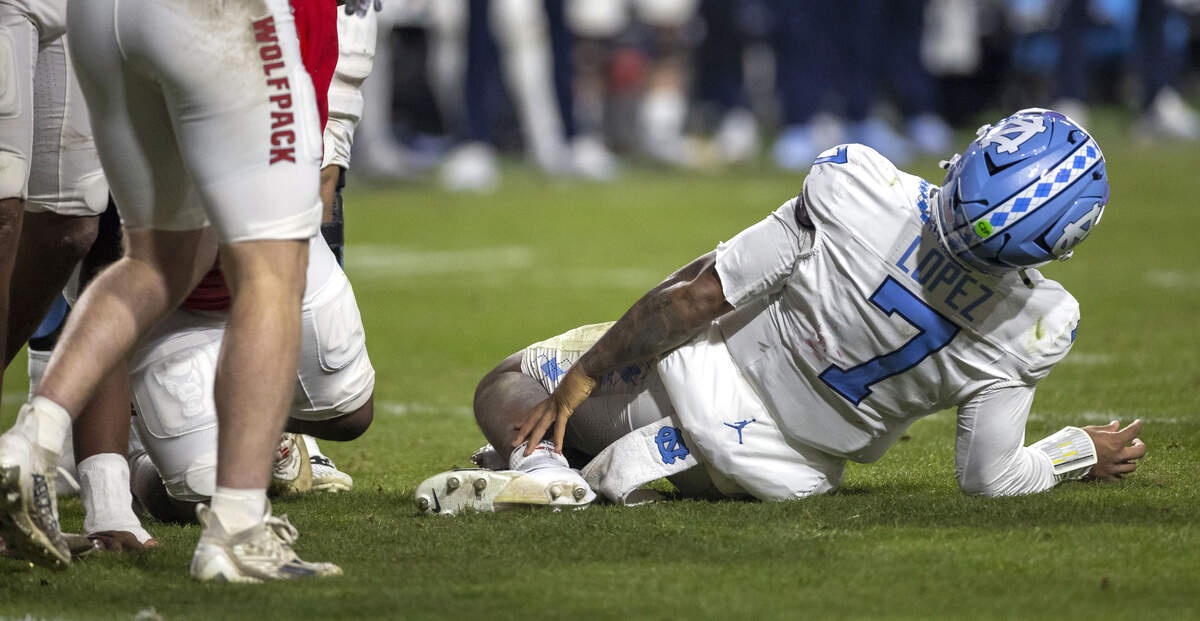 North Carolina quarterback Gio Lopez (7) grabs his ankle after being injured on a sack by N.C. State defensive tackle Brandon Cleveland (44) in the third quarter on Saturday, November 29, 2025 at Carter-Finley Stadium in Raleigh, N.C.