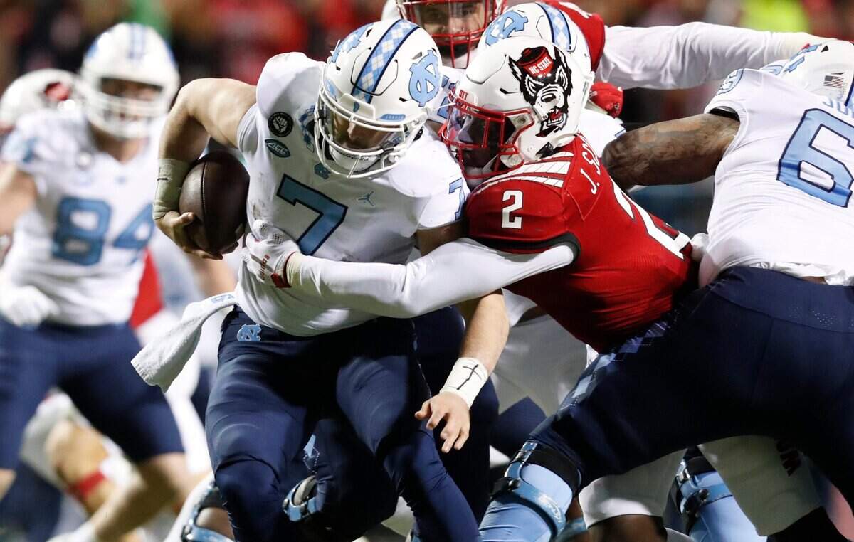 N.C. State linebacker Jaylon Scott (2) sacks North Carolina quarterback Sam Howell (7) during the first half of N.C. States game against UNC at Carter-Finley Stadium in Raleigh, N.C., Friday, November 26, 2021.