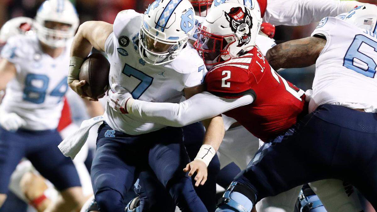N.C. State linebacker Jaylon Scott (2) sacks North Carolina quarterback Sam Howell (7) during the first half of N.C. States game against UNC at Carter-Finley Stadium in Raleigh, N.C., Friday, November 26, 2021.