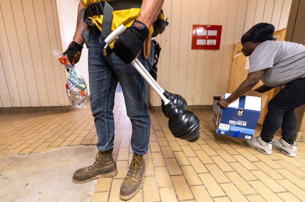Mateo Crane, with the grassroots group BeLoved Asheville, carries plungers to help residents in low-income independent living facilities, with no running water, flush their toilets on Wednesday, October. 8, 2024.. About half of Asheville’s water customers were still without running water this week because the remnants of Hurricane Helene ripped apart the city’s distribution system.