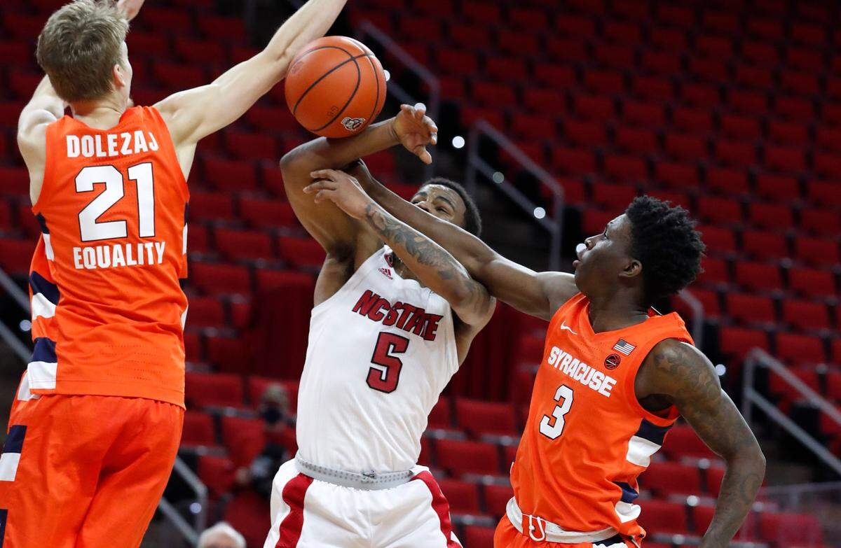 Syracuse’s Kadary Richmond (3) knocks the ball from N.C. State’s Thomas Allen (5) as Syracuse’s Marek Dolezaj (21) also defends during the first half of N.C. State’s game against Syracuse at PNC Arena in Raleigh, N.C., Tuesday, February 9, 2021.