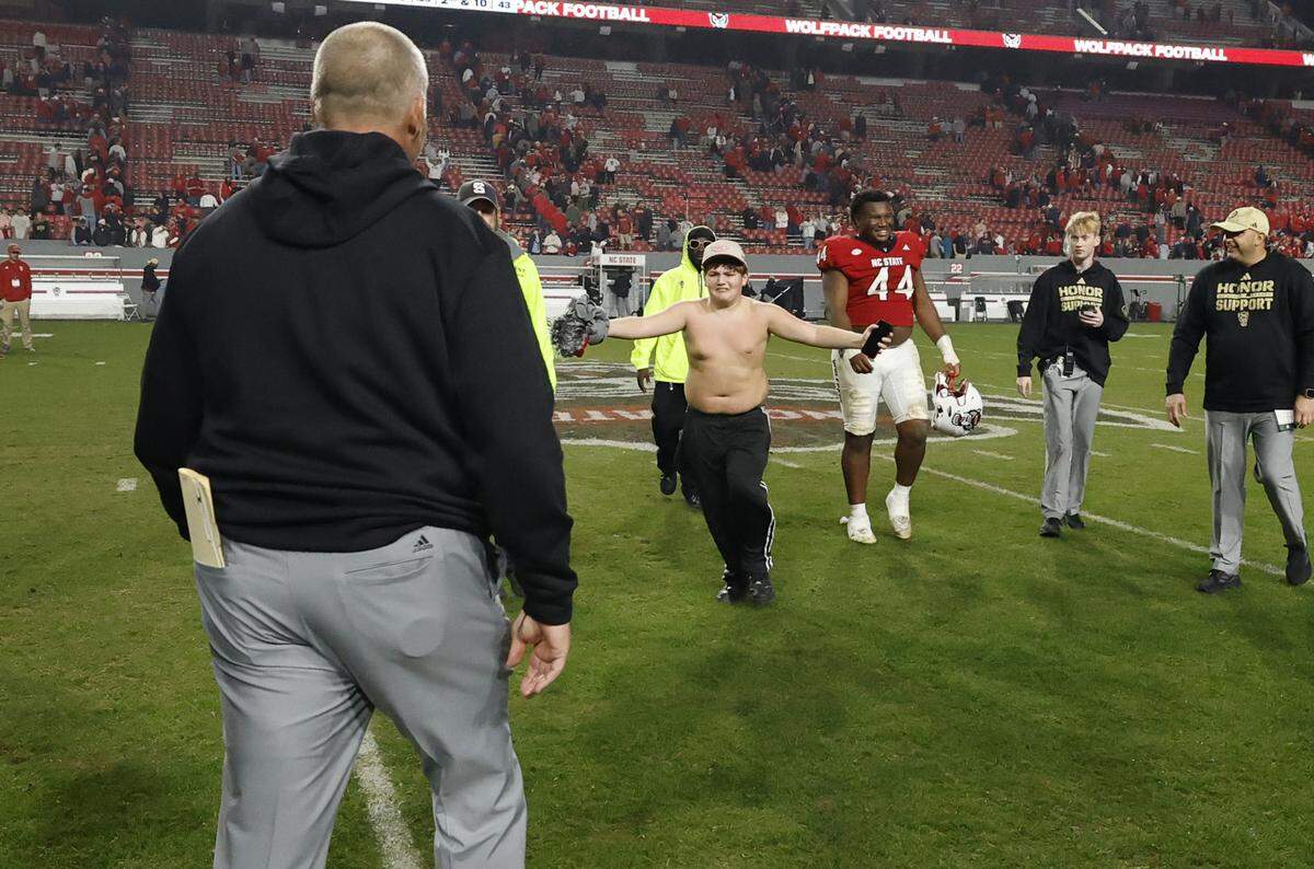 Jackston McDuffie, 12, runs to hug head coach Dave Doeren after the Wolfpack’s 21-11 victory over Florida State at Carter-Finley Stadium in Raleigh, North Carolina, on Friday, Nov. 21, 2025.
