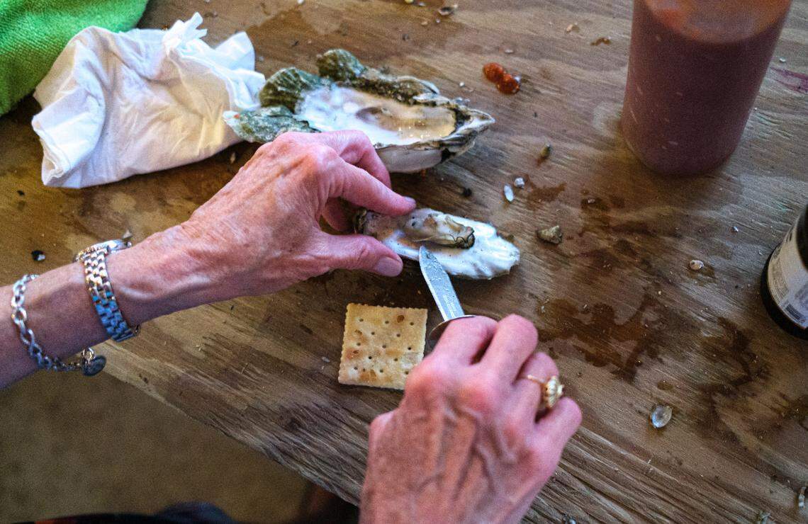 An oyster is carefully removed from it’s shell and placed on a saltine cracker with tobacso sauce, one of the many ways customers enjoy oysters at Bowen’s Island Restaurant. Bowen’s Island Restaurant hosts an oyster roast event for a wedding rehearsal party with some of the season’s first oysters from the Folly River near Charleston, S.C. Oct. 8, 2021.