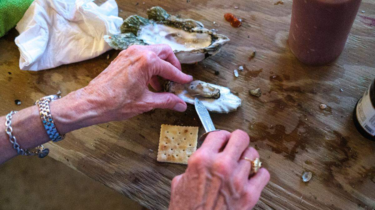 An oyster is carefully removed from it’s shell and placed on a saltine cracker with tobacso sauce, one of the many ways customers enjoy oysters at Bowens Island Restaurant near Charleston, S.C. Oct. 8, 2021.