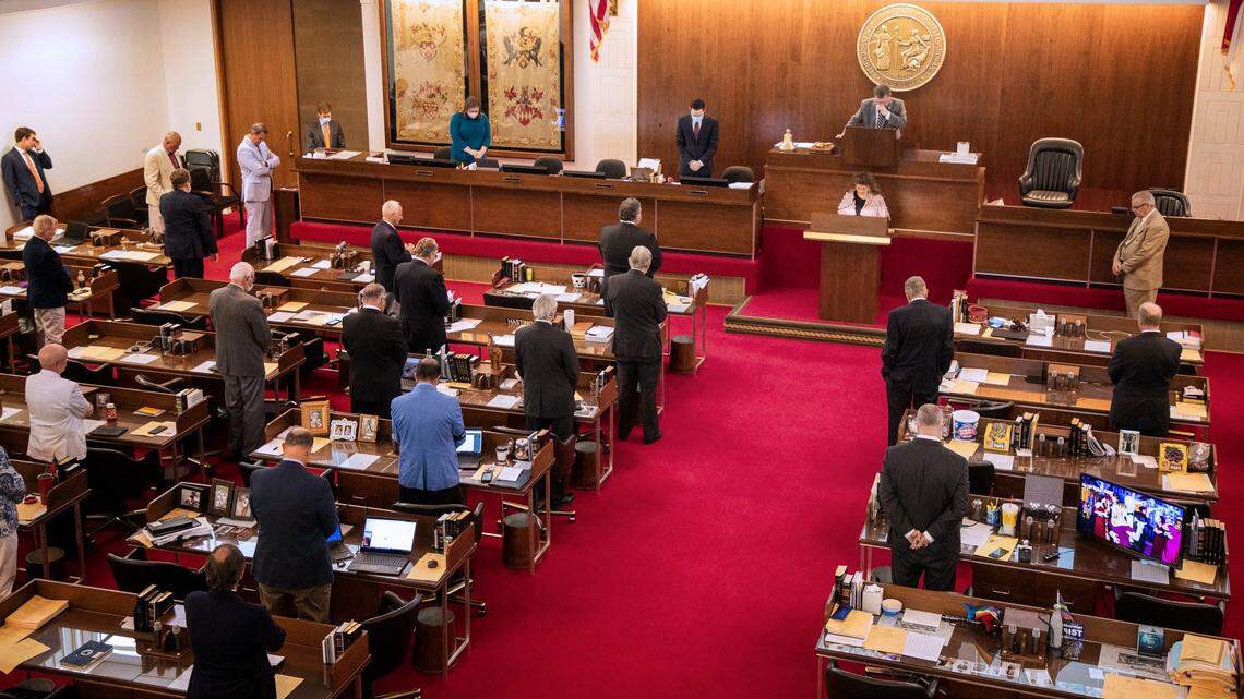 Members of the N.C. House of Representatives stand in prayer before finalizing versions of a bill allocating $3.5 billion in new federal money for COVID-19 relief, on Saturday, May 2, 2020, in the North Carolina General Assembly building in Raleigh, N.C.