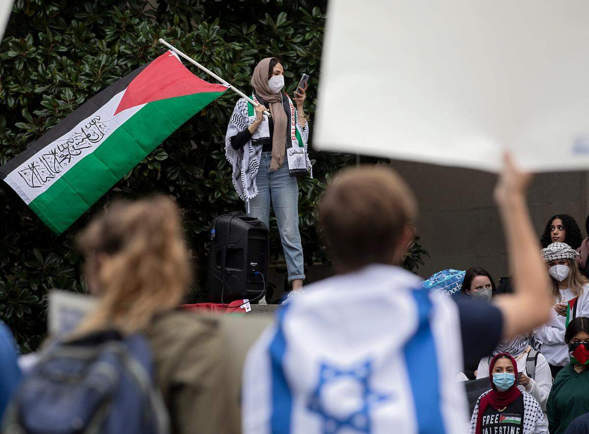 A person waves a Palestinian flag as a counter-protester wears an Israeli flag during a rally in support of Palestinians at UNC-Chapel Hill on Thursday, Oct. 12, 2023. The rally was organized by the UNC chapter of Students for Justice in Palestine.
