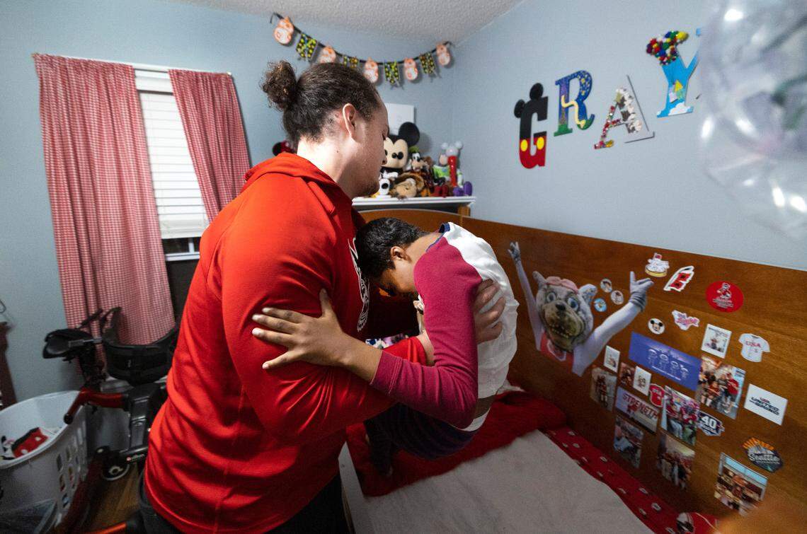 N.C. State offensive lineman Dylan McMahon lifts Grayson Ketchie from his bed at Grayson’s home in Garner Wednesday evening, Oct. 18, 2023. Ketchie, 12, has been suffering from severe neurological issues since he was a baby. He has been a Wolfpack fan since he was three and the players made a surprise visit to his home that evening.
