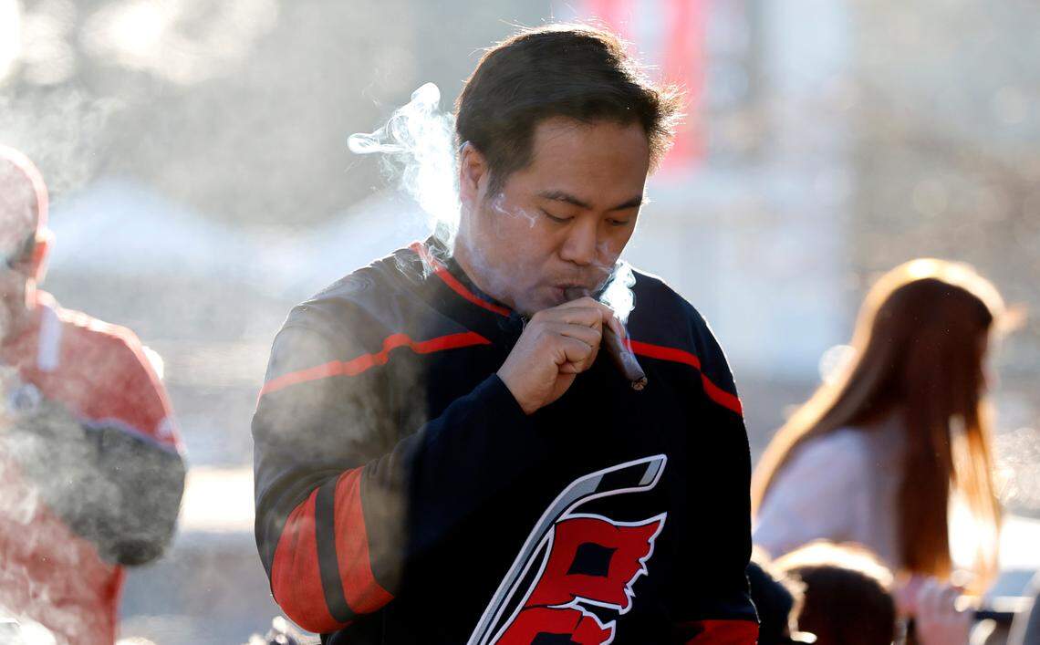 Eric Musico smokes a cigar as he tailgates with friends before the NHL Stadium Series game between the Carolina Hurricanes and the Washington Capitals at Carter-Finley Stadium in Raleigh, N.C., Saturday, Feb. 18, 2023.