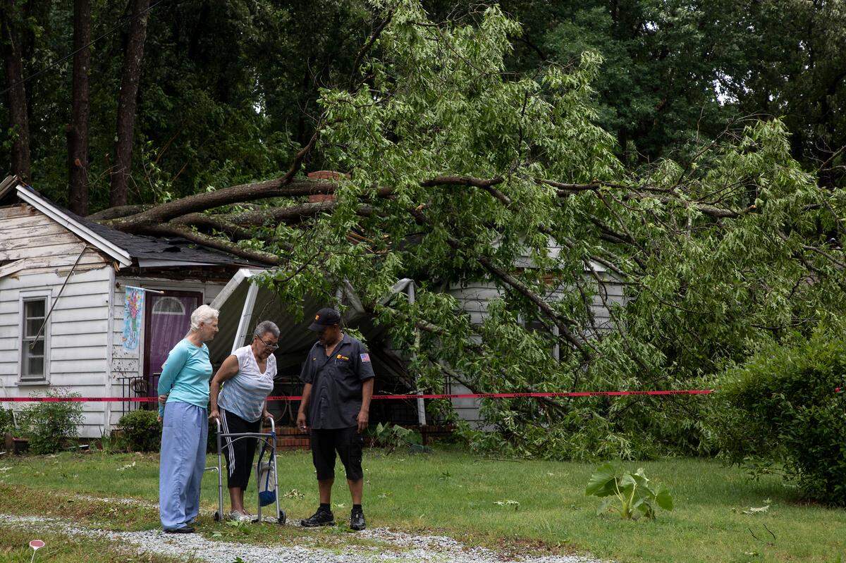 Nannie Smith, center, and her son, Terry Smith, walk with their neighbor, Vanessa Thornburg, after a tree fell on their house during strong storms on Monday, May 23, 2022, in Durham, N.C.