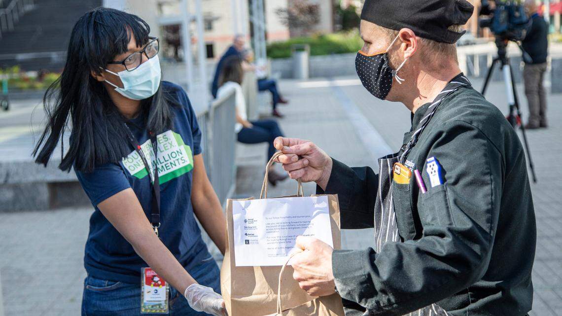 Centerplate catering employee Natasha Pennamon gives complementary bagged meals to Marriott chef Michael Hicks outside the Raleigh Convention Center Wednesday, May 14, 2020. The caterer donated free curbside meals to service industry employees Wednesday afternoon.