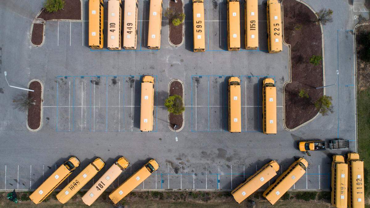 School buses sit in their designated parking lot on the empty campus of Green Hope High School in Cary, N.C. on the afternoon of Thursday, March 26, 2020. Wake County Public Schools have been closed since March 15 to curb the spread of COVID-19.