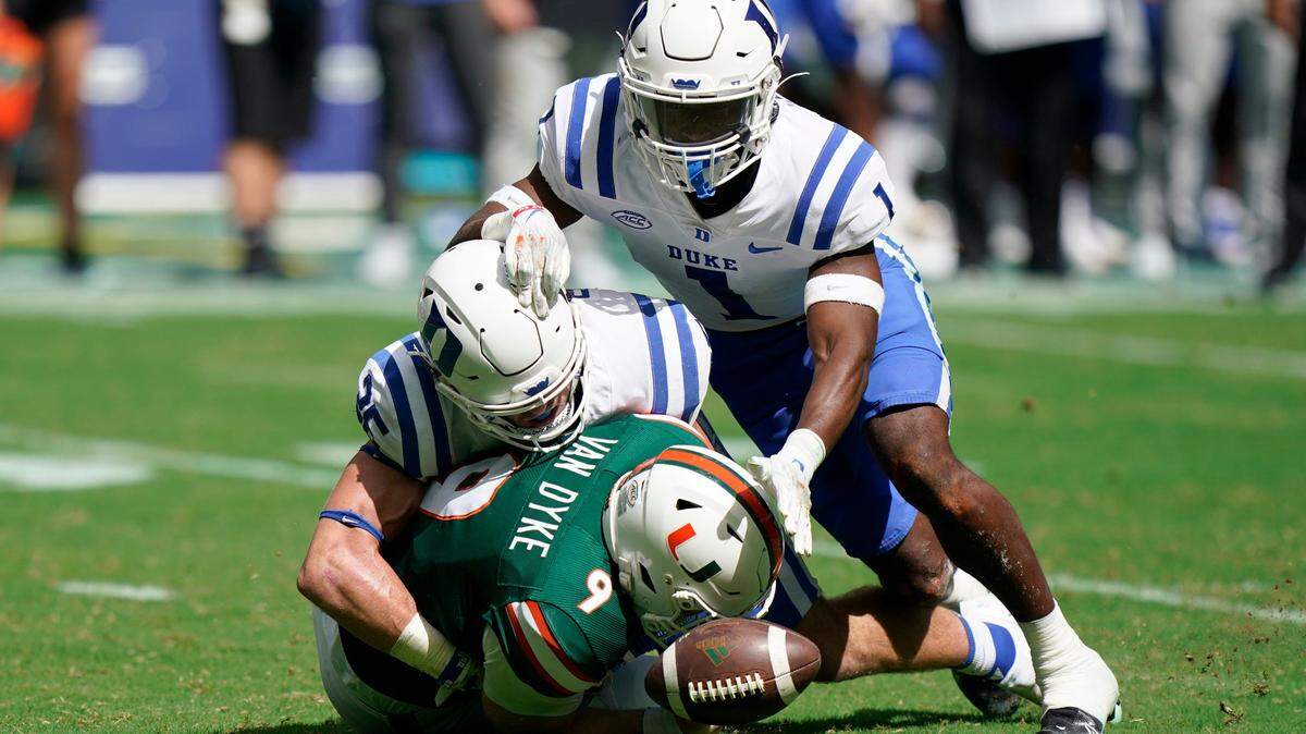 Miami quarterback Tyler Van Dyke (9) fumbles the ball as he is taken down by Duke linebacker Cam Dillon and defensive back Darius Joiner (1) during the first half of an NCAA college football game, Saturday, Oct. 22, 2022, in Miami Gardens, Fla. (AP Photo/Wilfredo Lee)