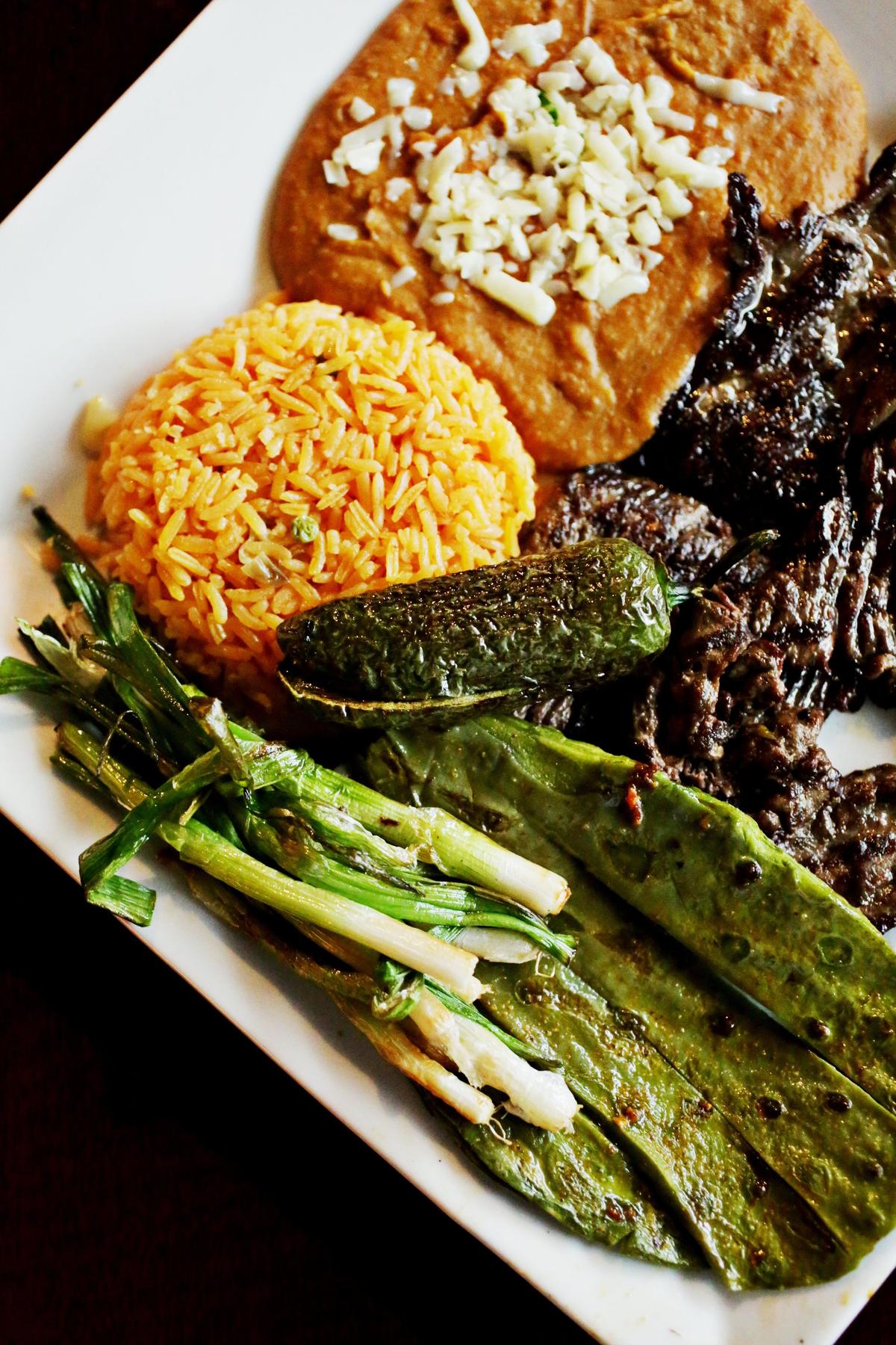 Cocula’s Carne Asada serves up an ample slab of marinated skirt steak, buried under a mixed grill of nopales, green onions and a whole jalapeno. Rice, beans, a side plate of avocado salad and homemade tortillas make for a fine roll-your-own taco feast.