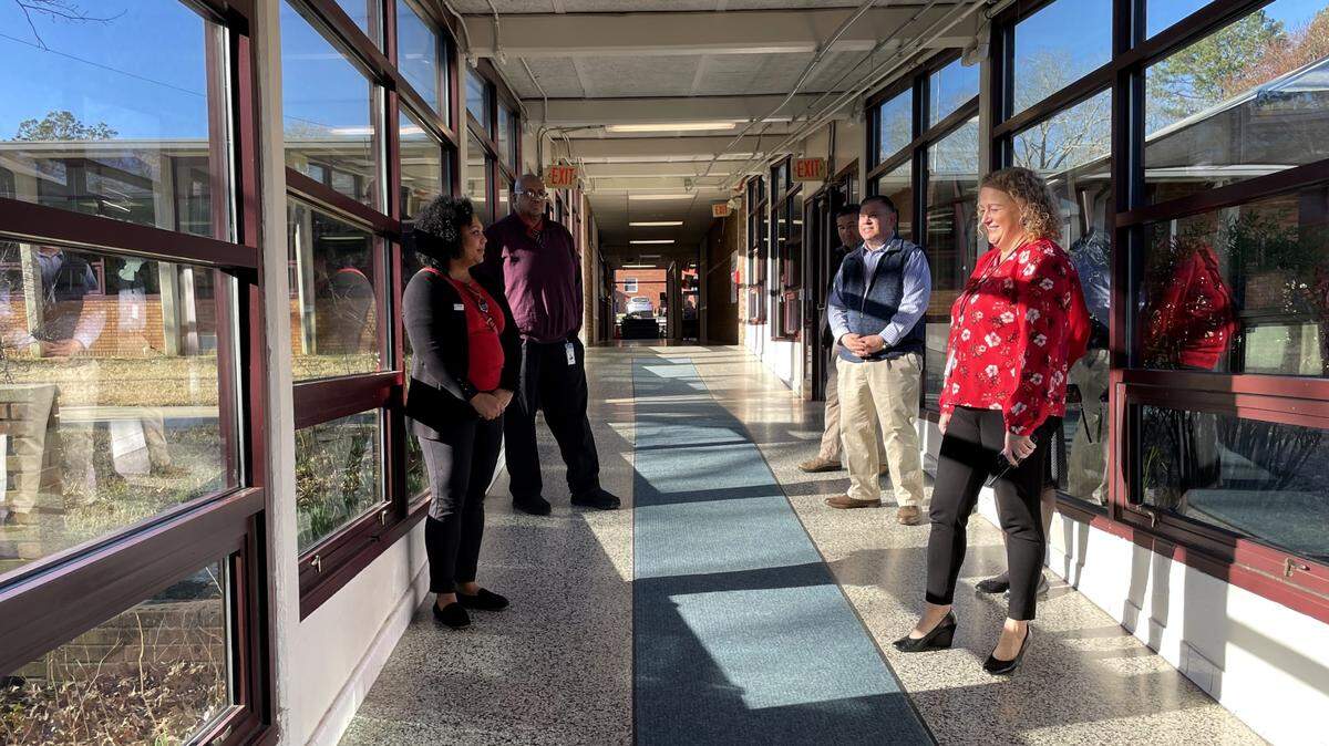 CHCCS board Vice Chair Riza Jenkins (clockwise, from left), Chief Operations Officer André Stewart, Deputy Superintendent for Operations Al Ciarochi and Carrboro Elementary School Principal Jennifer Halsey pause in a hallway that slopes with the land, cause stormwater issues when it rains.