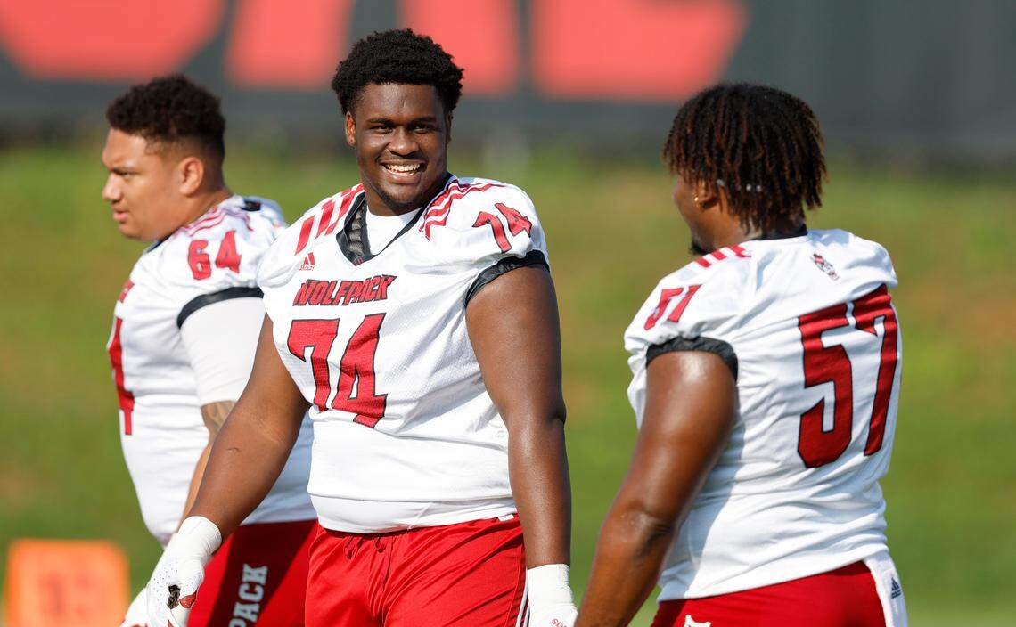 N.C. State’s Anthony Belton (74) laughs with Lyndon Cooper (57) during the Wolfpack’s first practice of fall camp in Raleigh, N.C., Wednesday, August 3, 2022.