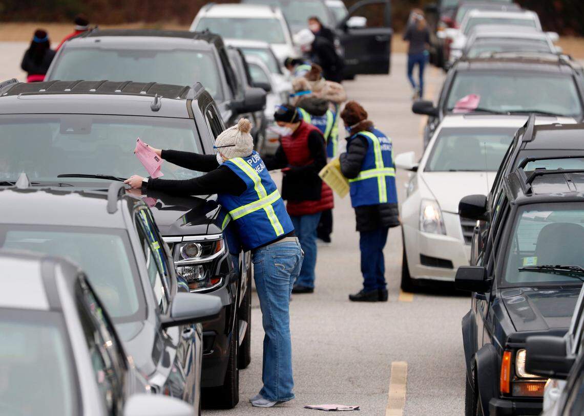 Registration information is collected from seniors lined up in their vehicles to get their COVID vaccine shot during a drive-thru COVID vaccination clinic at North Johnston High School in Kenly, N.C., Thursday, January 14, 2021.