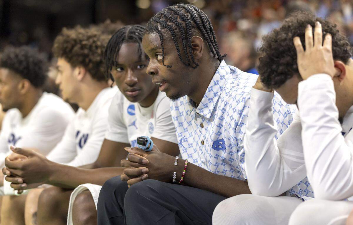 North Carolina forward Caleb Wilson, out with a broken thumb, talks with teammate Isaiah Denis (5), left, as Elijah Davis (6) covers his head, as the overtime period  against VCU begins on Thursday, March 18, 2026, during the first round of the NCAA Tournament at Bon Secours Arena in Greenville, S.C.