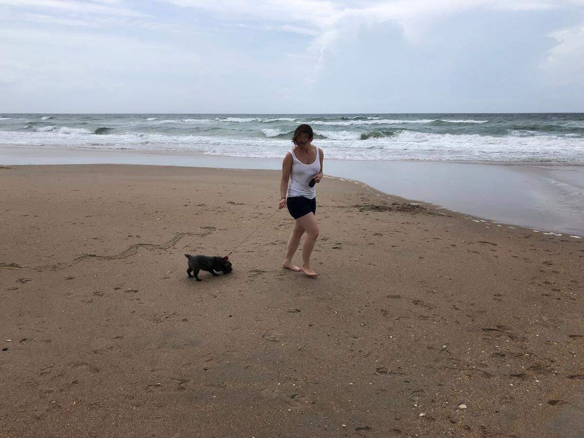 Laryssa Coogan of Lynchburg, Va., takes Jazzie, a Maltese mix, for a walk along the beach at Surf City, NC, on May 27, 2022, “so she can take a break from life, too,” Coogan said.