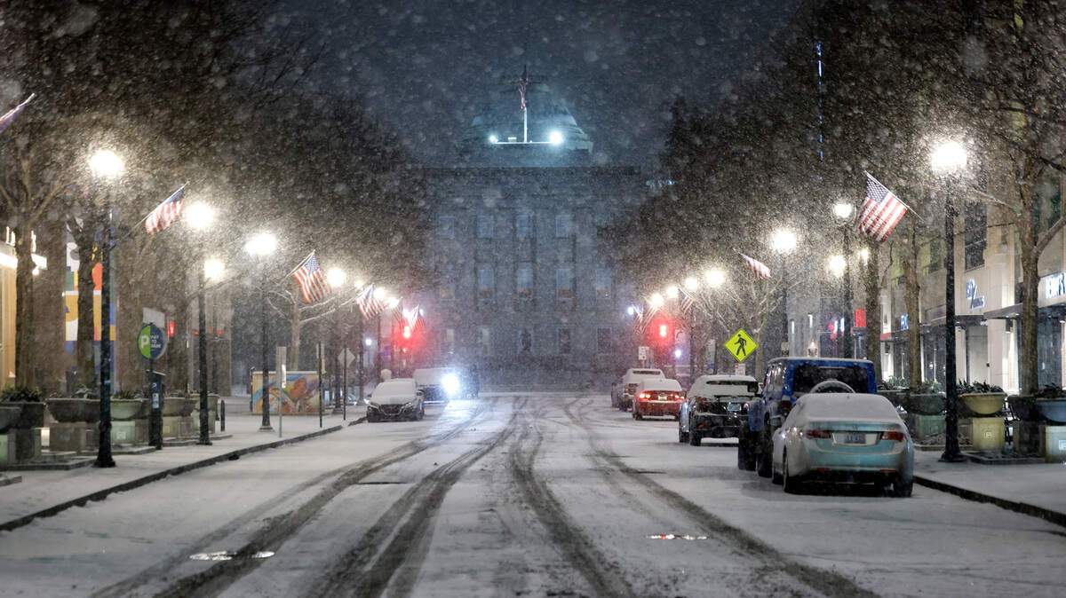 Snow falls on a quiet Fayetteville St. in downtown Raleigh, N.C., Tuesday evening, Jan. 21, 2025. School officials say worsening conditions led them to close schools on Wednesday.