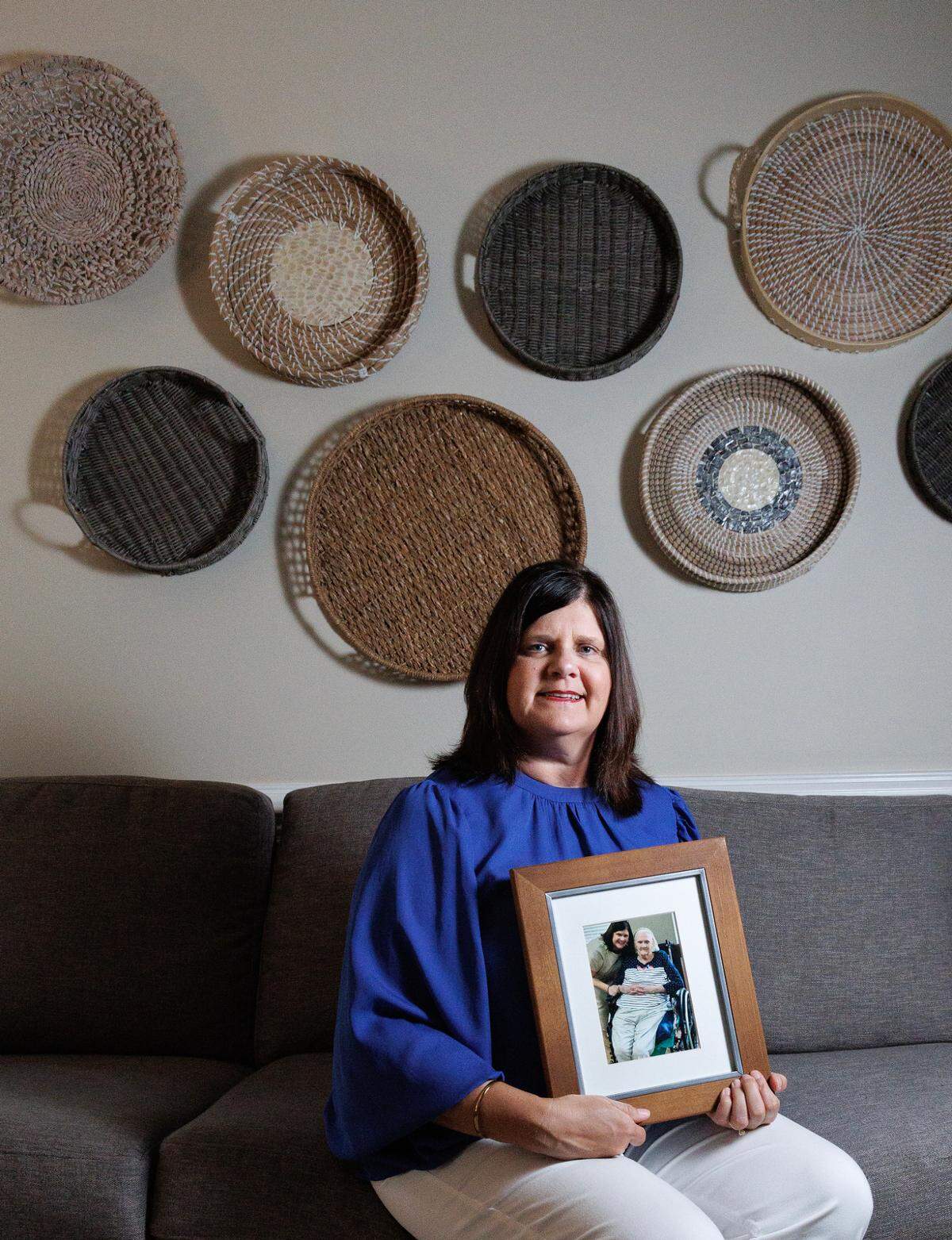 Sarah Cope, photographed on Tuesday, June 17, 2025, at her home in Garner, N.C., holds a photograph of herself and her mother, Linda Davis. Davis, who was diagnosed with dementia, lives in a nursing home in Harnett County. Cope says without Medicaid, she’s unsure how her family would care for her mother.