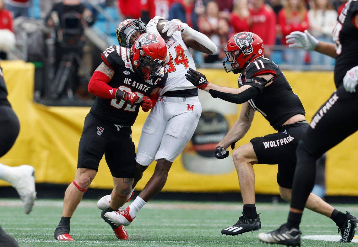 N.C. State linebacker Drake Thomas (32) hits Maryland tight end Corey Dyches (84) as linebacker Payton Wilson (11) comes in during the first half of N.C. State’s game against Maryland in the Duke’s Mayo Bowl at Bank of America Stadium in Charlotte, N.C., Friday, Dec. 30, 2022.