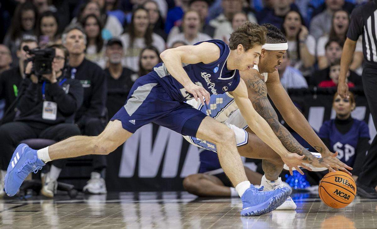 Saint Peters’ Doug Edert (25) and North CarolinaÕs Armando Bacot (5) chase a loose ball in the first half during the NCAA East Regional final on Sunday, March 27, 2022 at Wells Fargo Center in Philadelphia, Pa.