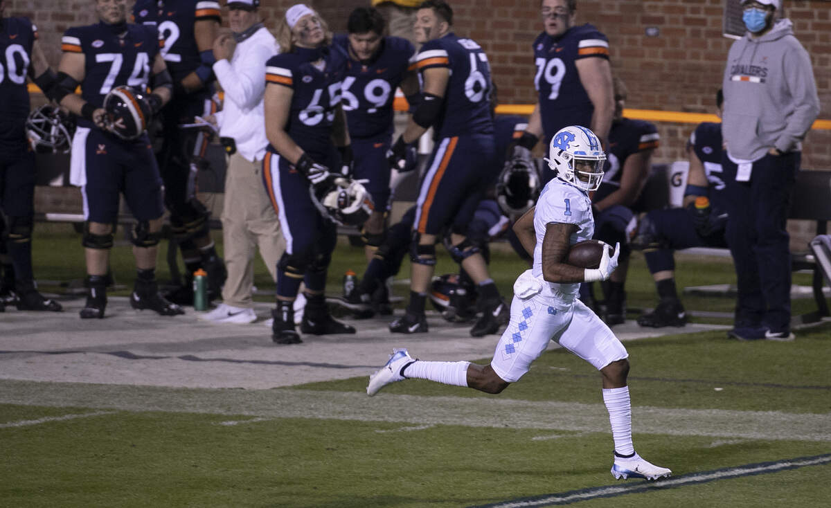 North Carolina’s Khafre Brown (1) races past the Virginia bench on a 76-yard pass reception from quarterback Sam Howell (7) or a touchdown in the second quarter on Saturday, October 31, 2020 at Scott Stadium in Charlottesville, Va.