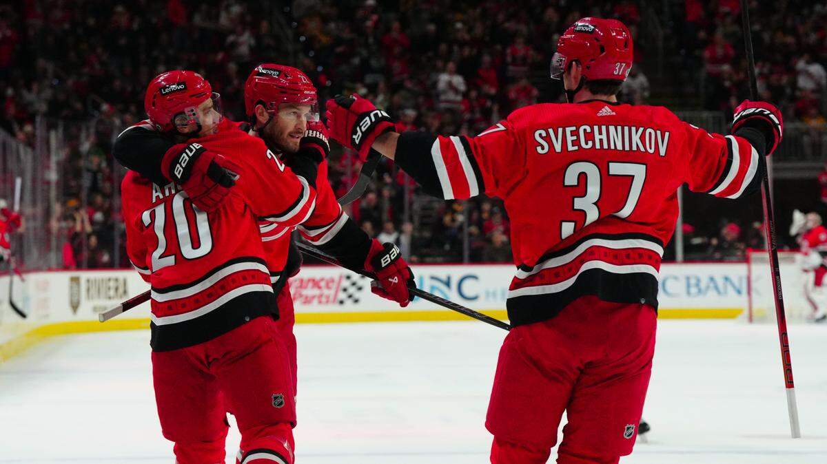 Jan 13, 2024; Raleigh, North Carolina, USA; Carolina Hurricanes defenseman Brett Pesce (22) is congratulated by center Sebastian Aho (20) right wing Andrei Svechnikov (37) after his goal against the Pittsburgh Penguins during the first period at PNC Arena. Mandatory Credit: James Guillory-USA TODAY Sports