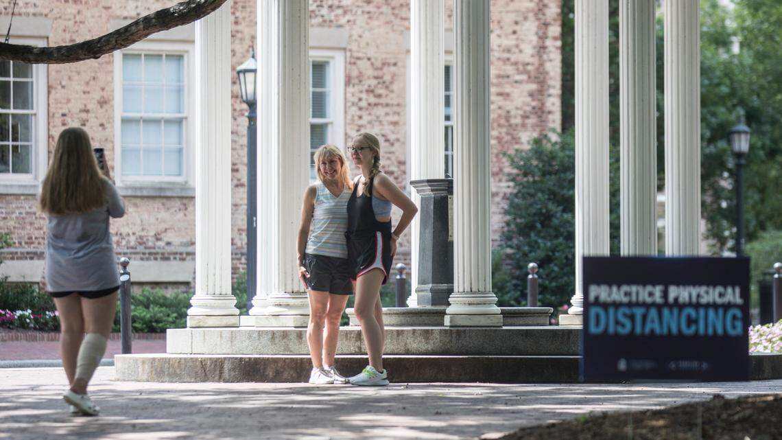First year student Brittany Maier takes a picture of first year student Erika Bradley and her mother Kim Bradley, who took off their masks to capture a moment, at the Old Well on UNC-Chapel Hill’s campus on Thursday, Aug. 6, 2020.
