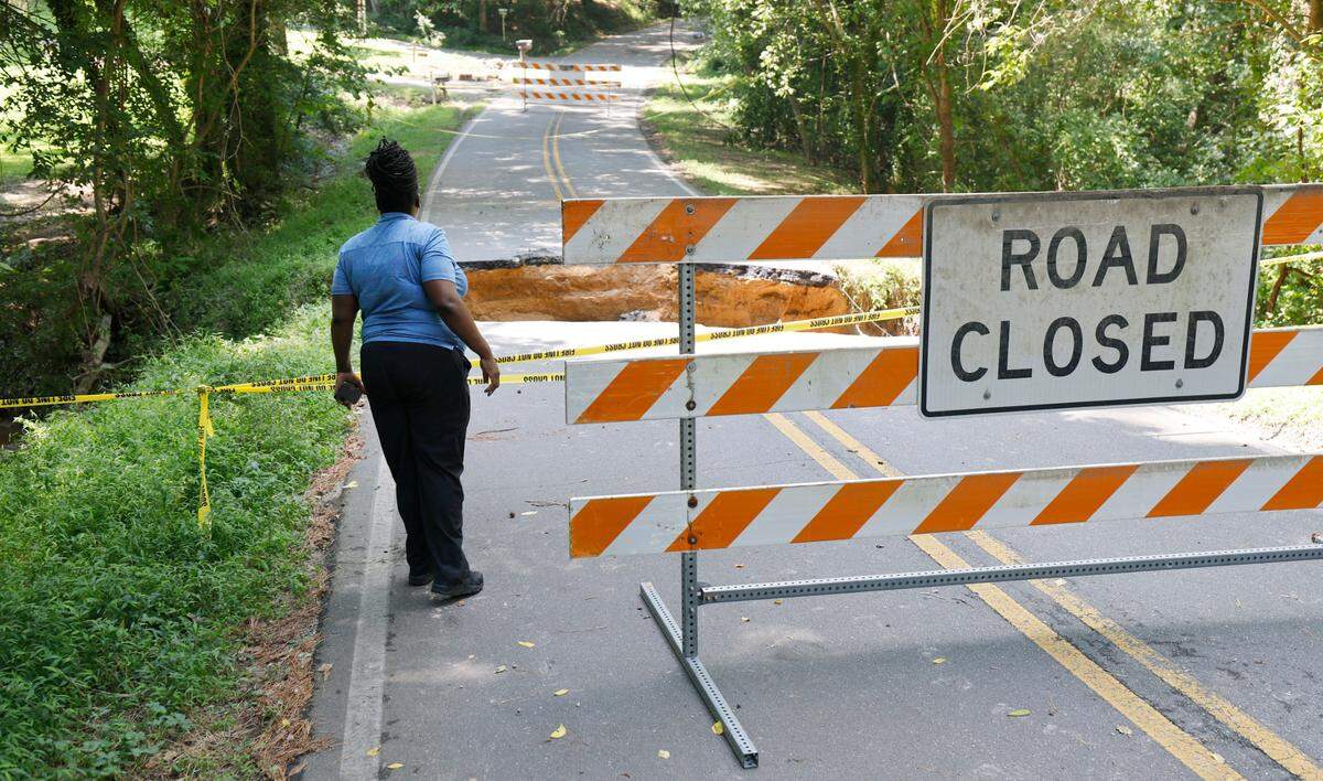 Germeka Carson looks at the washed away road on Dogwood Acres Drive in Chapel Hill, N.C., on Tuesday, July 8, 2025. The road was washed away when the remnants of Tropical Storm Chantal passed through the area.