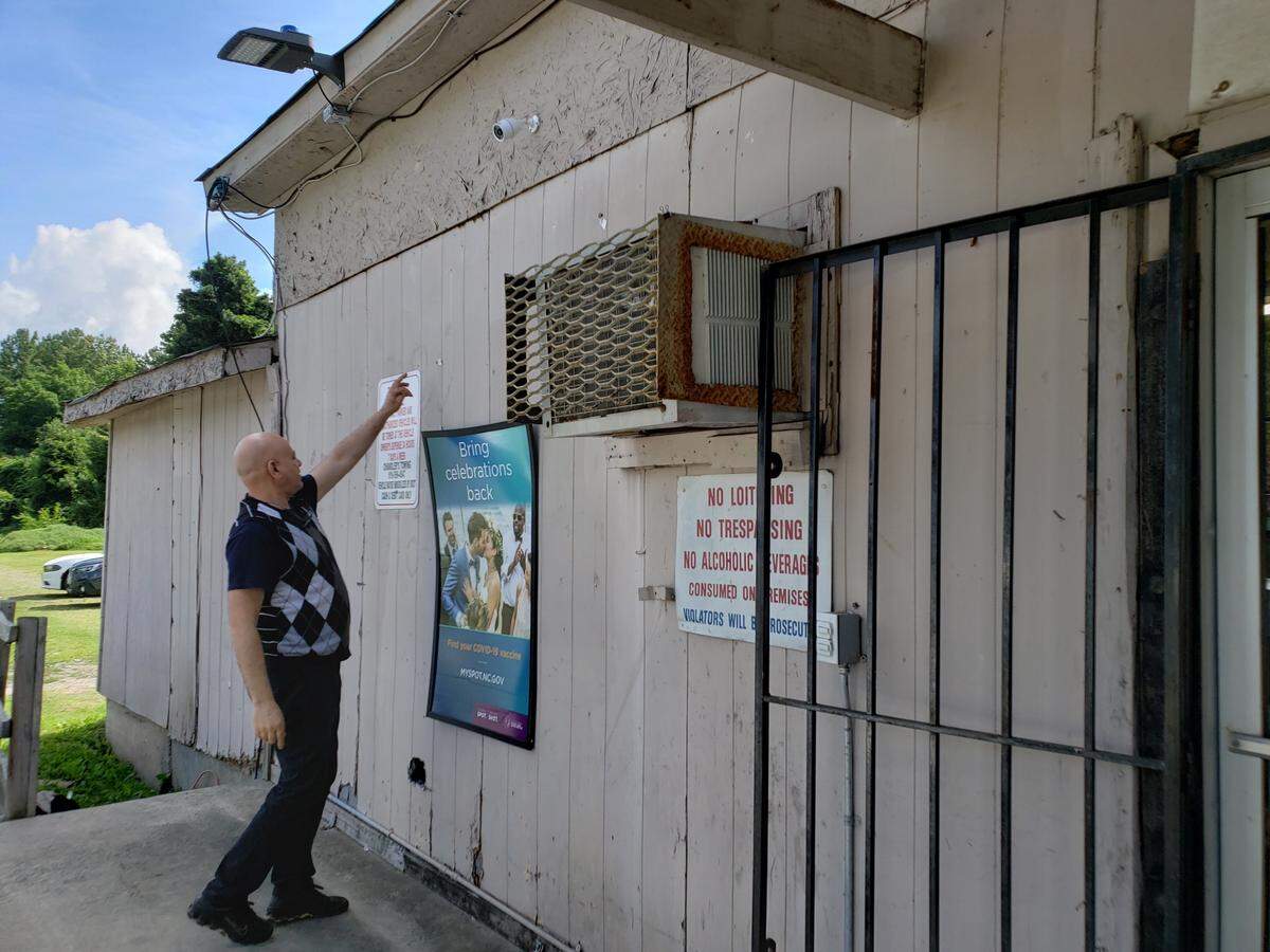 Salah Moustafa points to gunshot bullets at the Durham mini mart near the corner of Dearborn Drive and Martin Street on June 29, 2021.